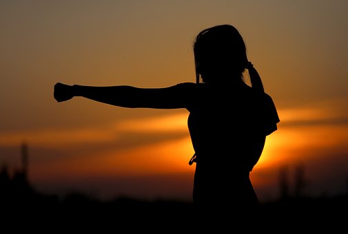 Man sieht die Silhouette einer Frau, die eine Boxbewegung macht. Im Hintergrund sieht man einen Sonnenuntergang